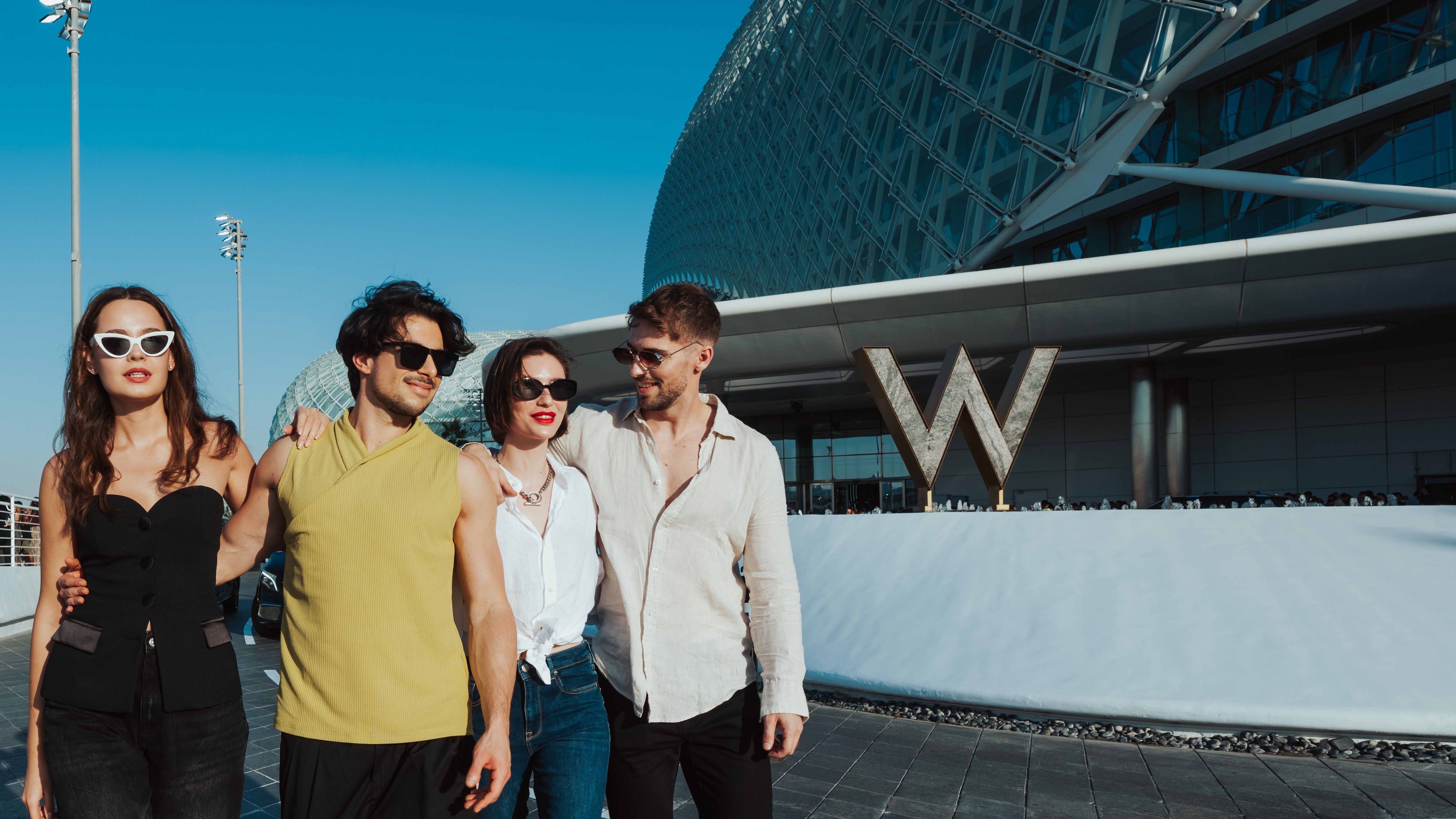Four people standing together in front of a modern building with a 'W' logo.
